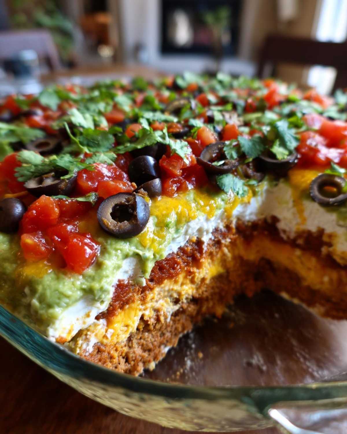 Close-up of a slice removed from a glass dish showing the distinct layers of the amazing 7 layer dip.