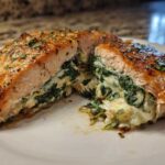 A perfectly cooked stuffed salmon fillet, cut in half to show the creamy spinach filling inside this amazing stuffed salmon.