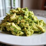 A mound of creamy, chunky avocado chicken salad served on a bright white plate.
