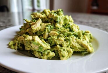 A mound of creamy, chunky avocado chicken salad served on a bright white plate.
