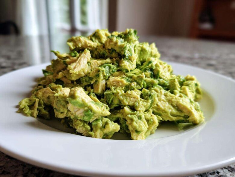 A mound of creamy, chunky avocado chicken salad served on a bright white plate.
