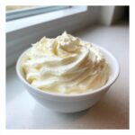 A white bowl filled with perfectly piped, creamy, and glossy sugar cookie icing.