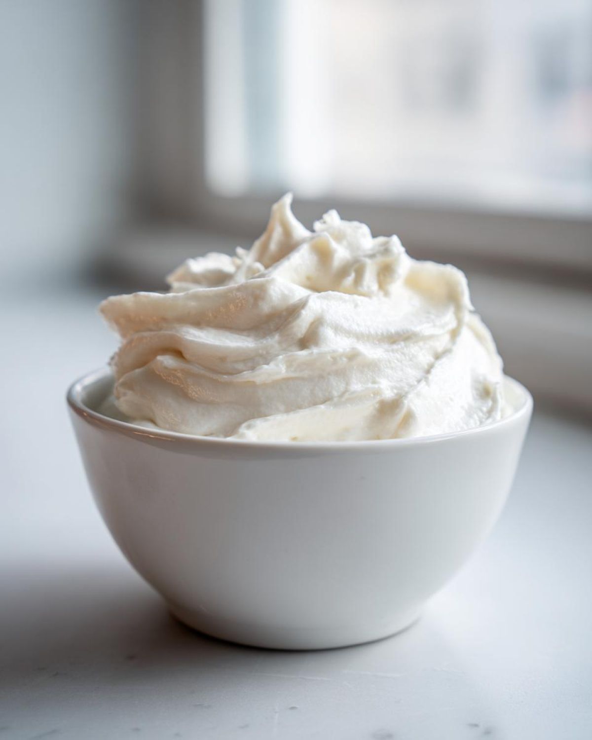 A white bowl filled with thick, perfectly piped sugar cookie icing, ready for decorating.