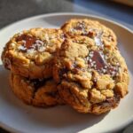 Close-up of three delicious brown butter chocolate chip cookies topped with flaky sea salt.