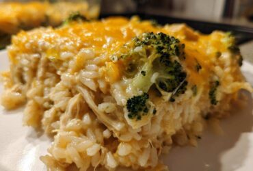 Close-up of a serving of creamy chicken broccoli rice casserole topped with melted cheddar cheese.