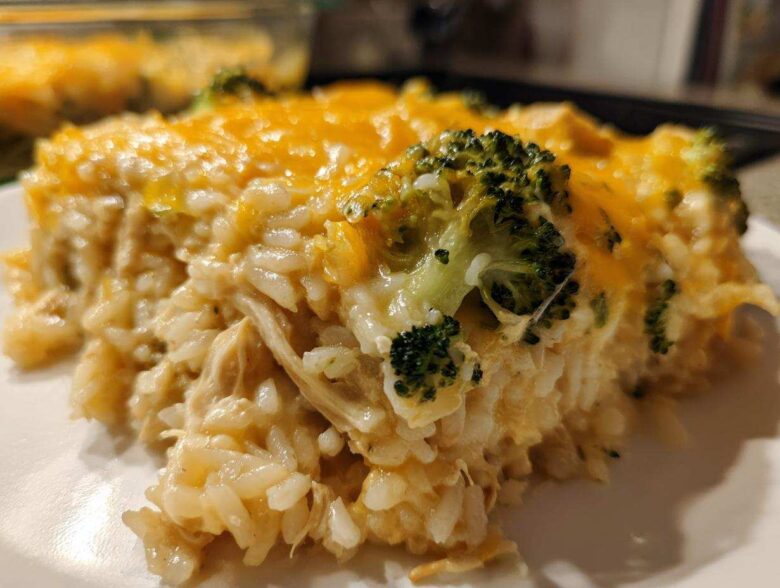 Close-up of a serving of creamy chicken broccoli rice casserole topped with melted cheddar cheese.