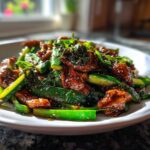 A close-up of a vibrant chicken zucchini stir fry coated in a glossy brown sauce, served on a white plate.