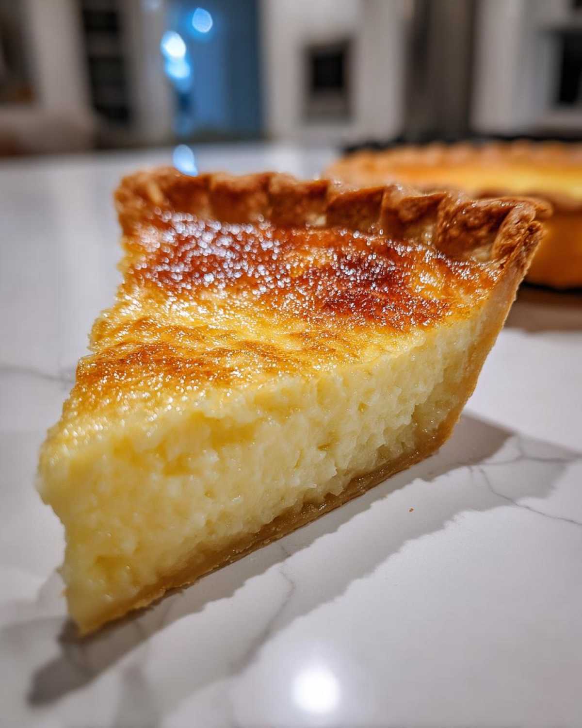 Close-up of a thick slice of creamy buttermilk pie showing the golden-brown, slightly caramelized top crust.