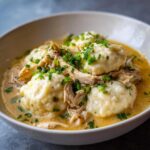 Close-up of a bowl of creamy chicken and dumpling topped with fresh chopped chives.