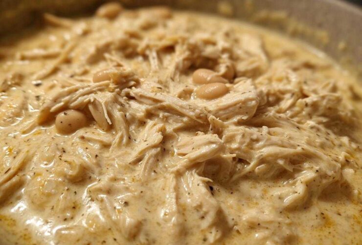Close-up of creamy white chicken chili recipe featuring shredded chicken and white beans in a rich sauce.