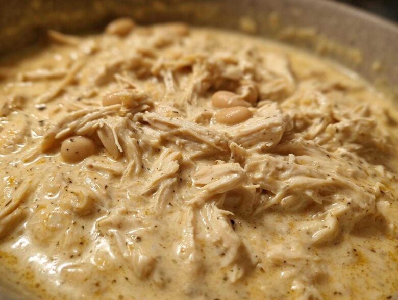 Close-up of creamy white chicken chili recipe featuring shredded chicken and white beans in a rich sauce.