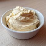 A close-up of rich, creamy garlic aioli, perfectly piped or spooned into a small white bowl.