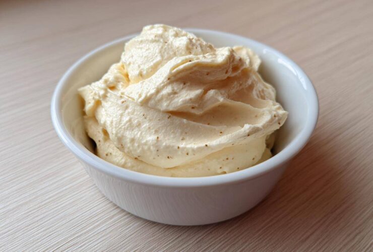 A close-up of rich, creamy garlic aioli, perfectly piped or spooned into a small white bowl.