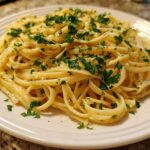 A close-up of a plate piled high with Creamy Lemon Pasta, tossed in a rich sauce and topped with fresh chopped parsley.