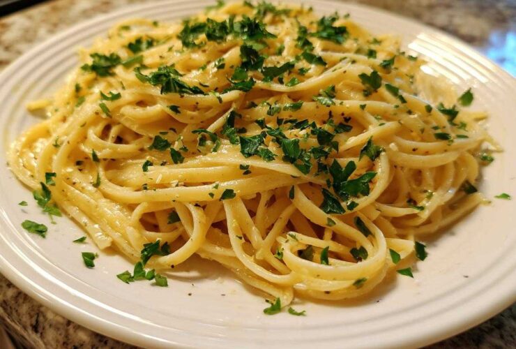 A close-up of a plate piled high with Creamy Lemon Pasta, tossed in a rich sauce and topped with fresh chopped parsley.
