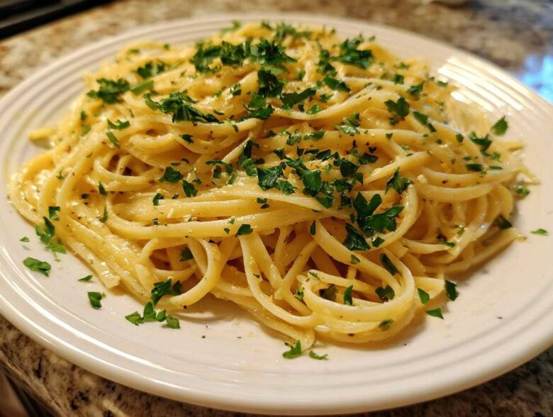 A close-up of a plate piled high with Creamy Lemon Pasta, tossed in a rich sauce and topped with fresh chopped parsley.