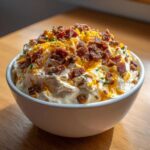 A creamy, loaded Million Dollar Dip topped generously with crumbled bacon, shredded cheddar cheese, and chives.