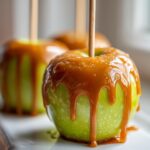 Close-up of a bright green apple covered in thick, dripping caramel sauce, ready to eat as one of the best caramel apples.