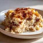 A close-up serving of creamy french onion butter rice topped generously with deeply caramelized onions.