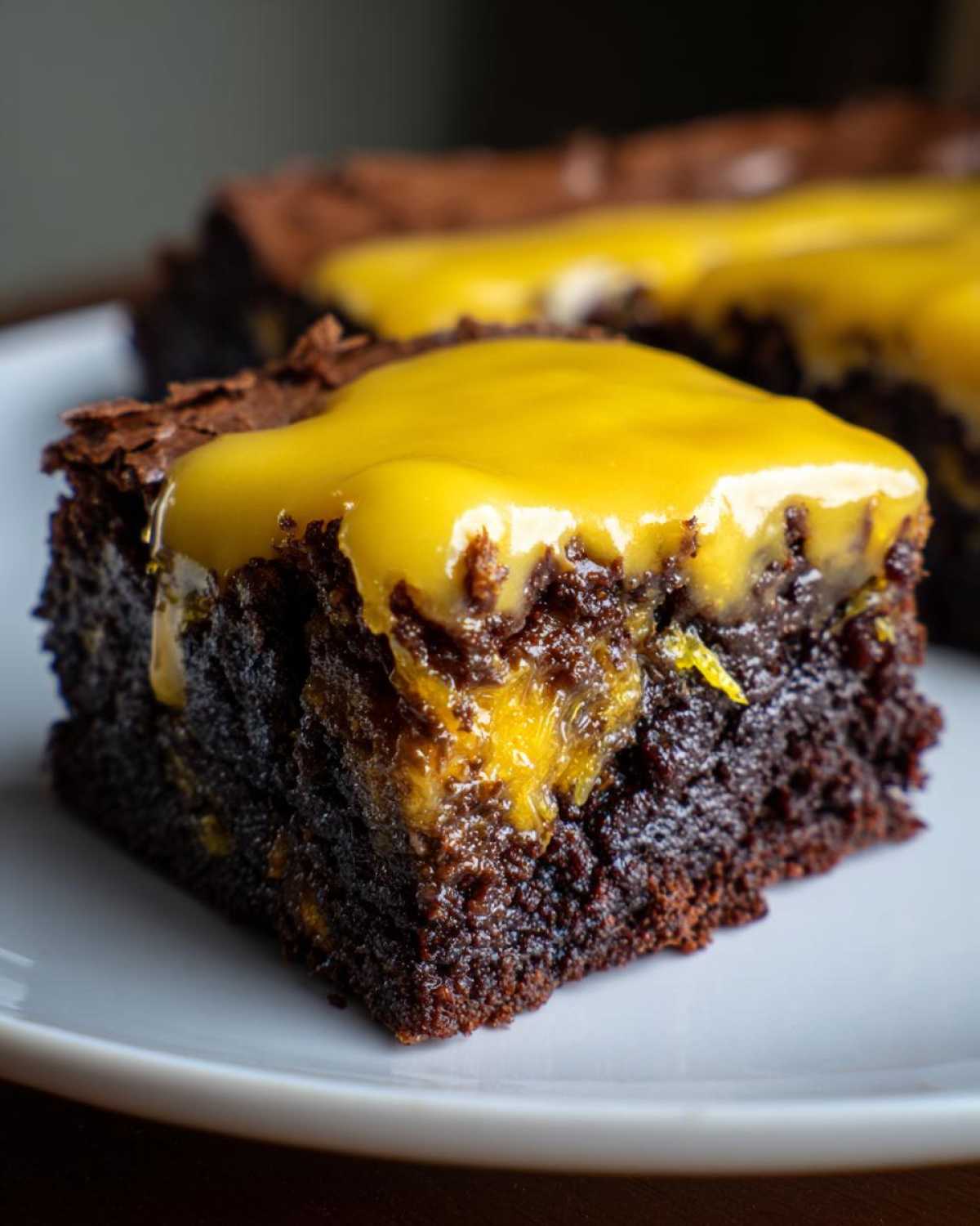 Close-up of a fudgy chocolate lemon brownies square topped with a thick, bright yellow lemon glaze.