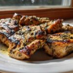 Close-up of grilled chicken pieces coated in a green herb chicken marinade, showing char marks.