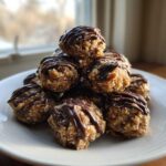 A stack of homemade pecan pie balls drizzled with dark chocolate on a white plate.