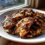 Close-up of grilled chicken pieces seasoned with herbs, showcasing the results of the perfect chicken marinade.