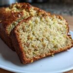 Close-up of moist zucchini banana bread, showing two slices cut from the loaf on a white plate.