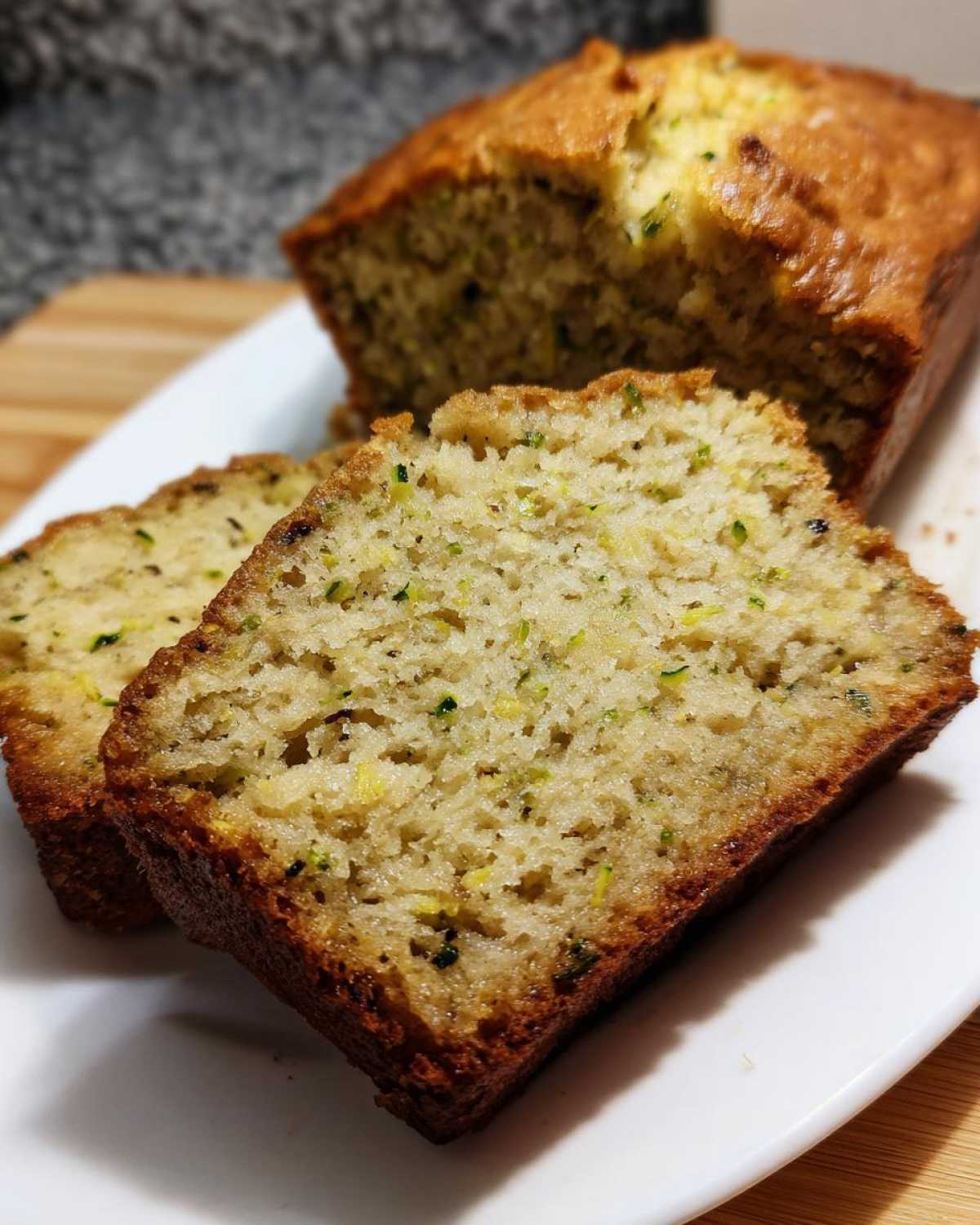 Close-up of moist slices of zucchini banana bread showing visible green shreds of zucchini in the crumb.