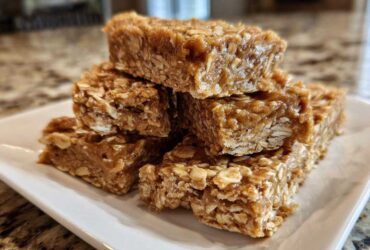 A stack of homemade, chewy no-bake protein bars made with oats, displayed on a rectangular white plate.