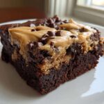 Close-up of a rich, fudgy banana bread brownies slice topped with peanut butter swirl and chocolate chips.