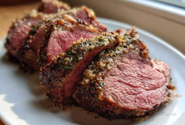 Close-up of medium-rare prime rib recipe slices showing a thick herb and garlic crust.