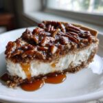 A thick slice of no-bake pecan pie dip with a creamy white layer, graham cracker crust, and topped with glazed pecans and caramel sauce.