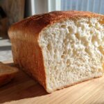 Close-up of a freshly baked loaf of soft sourdough sandwich bread, showing the fluffy, white interior crumb.
