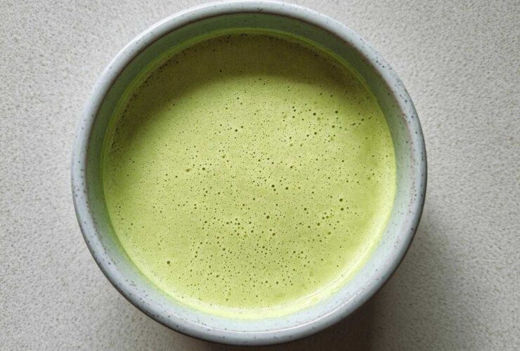 Overhead view of a bowl of bright green, velvety celery soup with a frothy top layer.