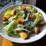 A close-up of a fresh caesar salad topped with grated Parmesan cheese and crunchy croutons.