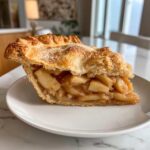 A close-up shot of a generous slice of amazing apple pie showing thick, cinnamon-spiced apple filling and a golden, flaky crust.