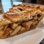 Close-up of a perfectly baked slice of apple pie showing flaky crust and thick apple filling.