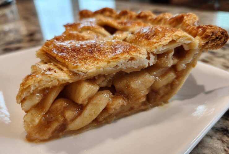 Close-up of a perfectly baked slice of apple pie showing flaky crust and thick apple filling.