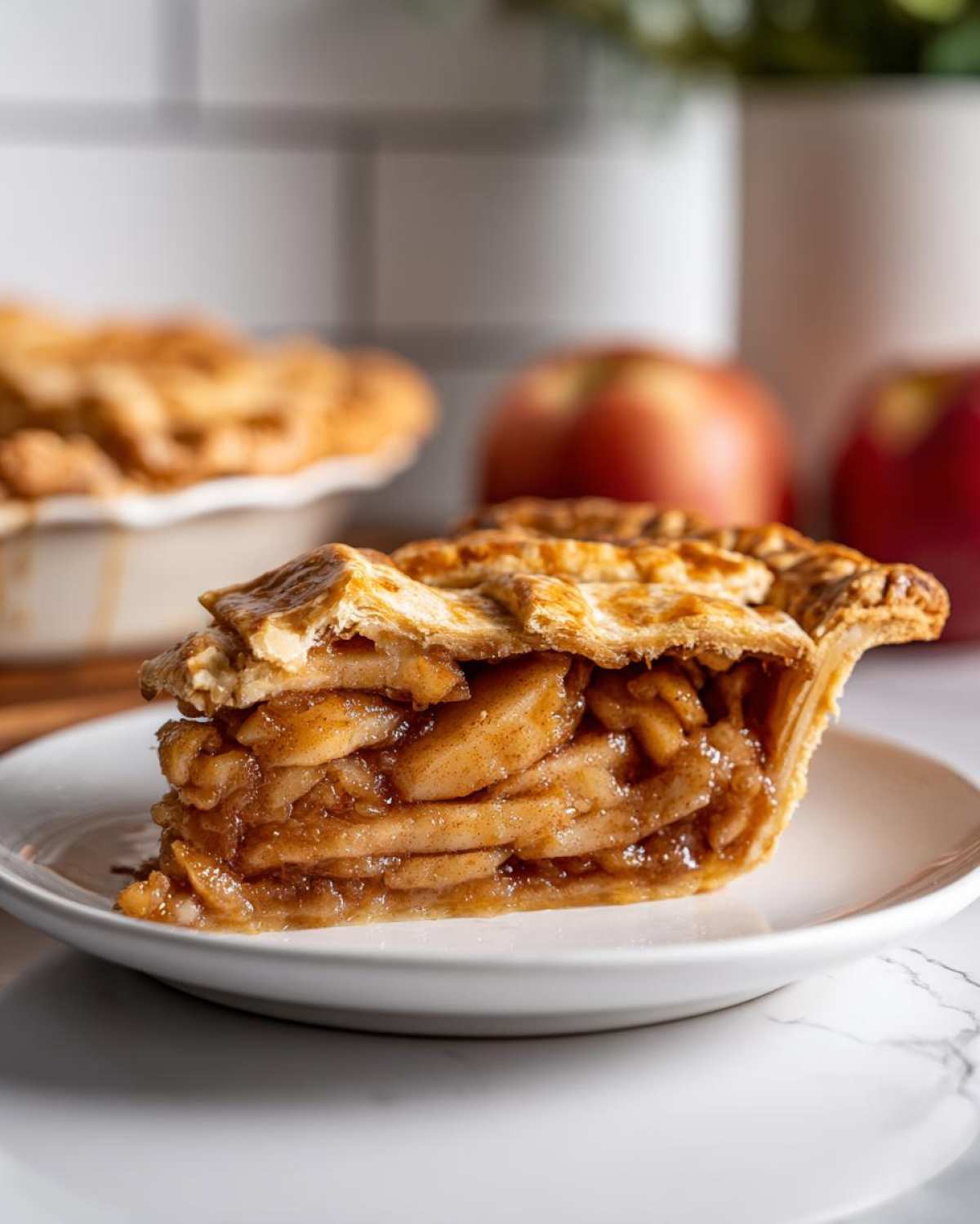 Close-up of a thick slice of amazing apple pie showing layered, cinnamon-spiced filling and golden lattice crust.