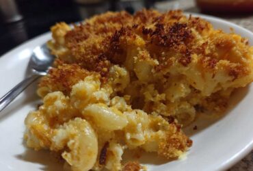 Close-up of a scoop of creamy baked mac and cheese recipe with a golden, crispy breadcrumb topping.
