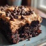 Close-up of a rich, dark chocolate banana bread brownies square topped with peanut butter frosting and mini chocolate chips.