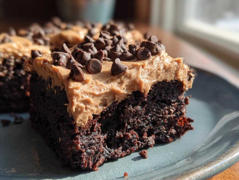 Close-up of a rich, dark chocolate banana bread brownies square topped with peanut butter frosting and mini chocolate chips.