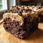 Close-up of a rich, dark chocolate banana bread brownies square topped with peanut butter frosting and mini chocolate chips.