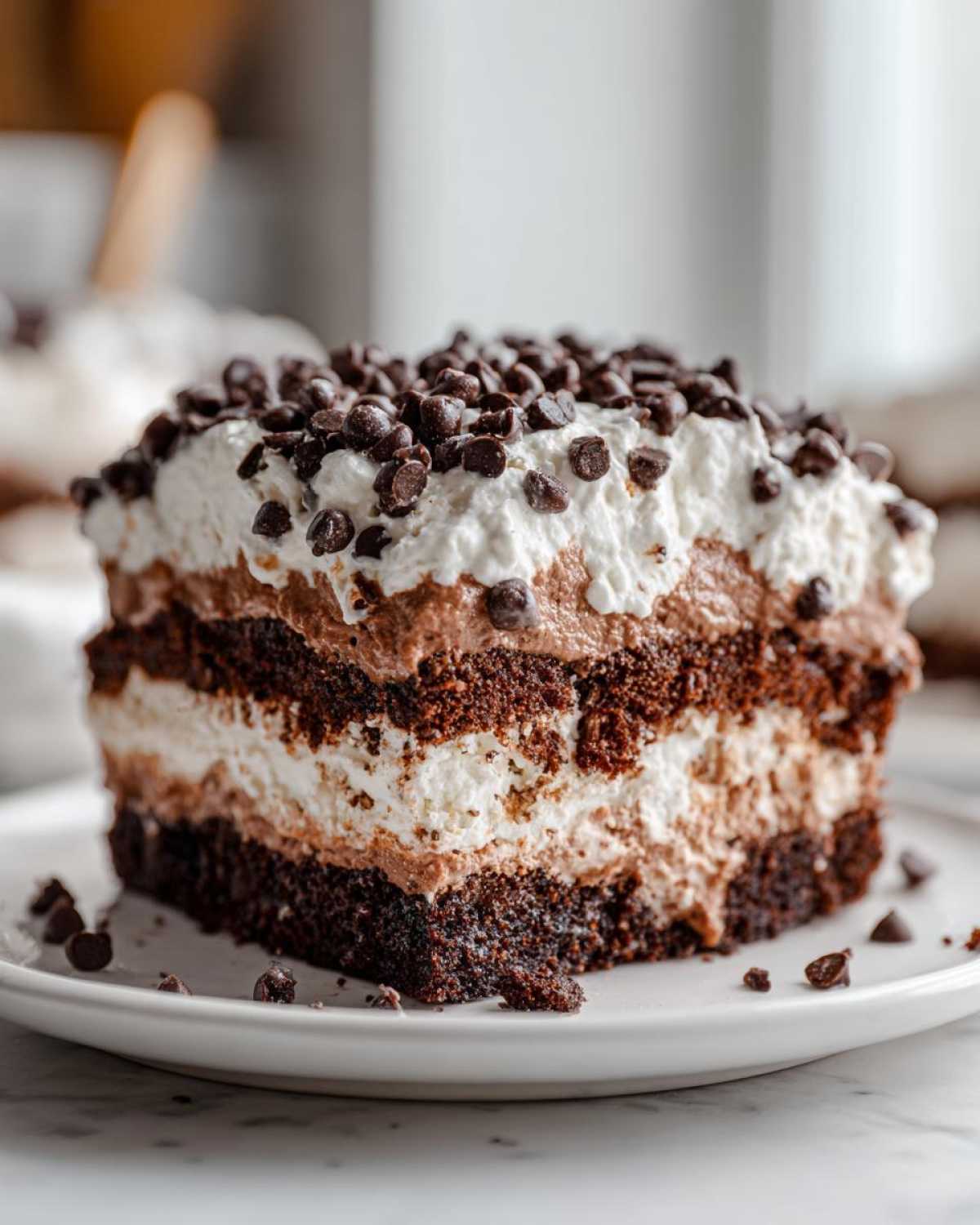A decadent, layered slice of brownie refrigerator cake topped with whipped cream and mini chocolate chips.