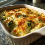 Close-up of a golden-brown, cheesy Chicken Divan casserole topped with bright green broccoli florets.