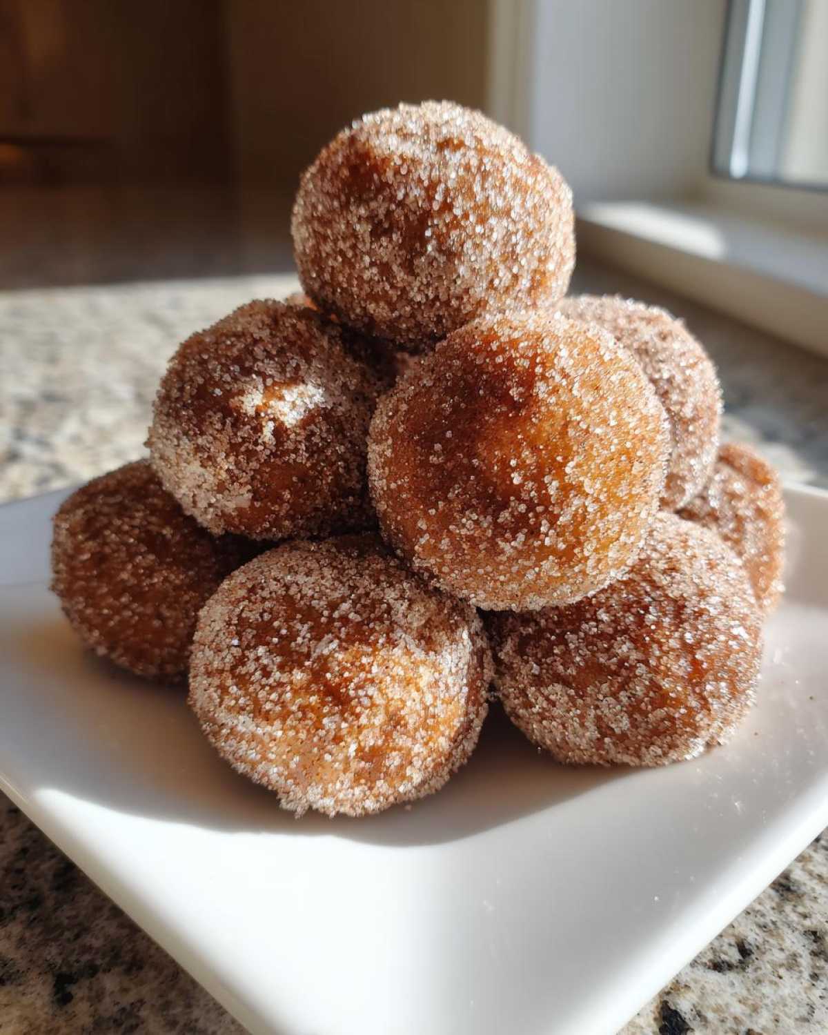 A stack of freshly made cinnamon sugar snowball cookies generously coated in sparkling sugar crystals.