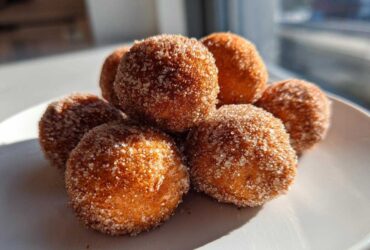 A stack of freshly made cinnamon sugar snowball cookies coated heavily in sparkling sugar.