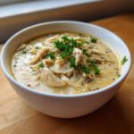 A close-up of creamy chicken wild rice soup topped with shredded chicken and fresh parsley.