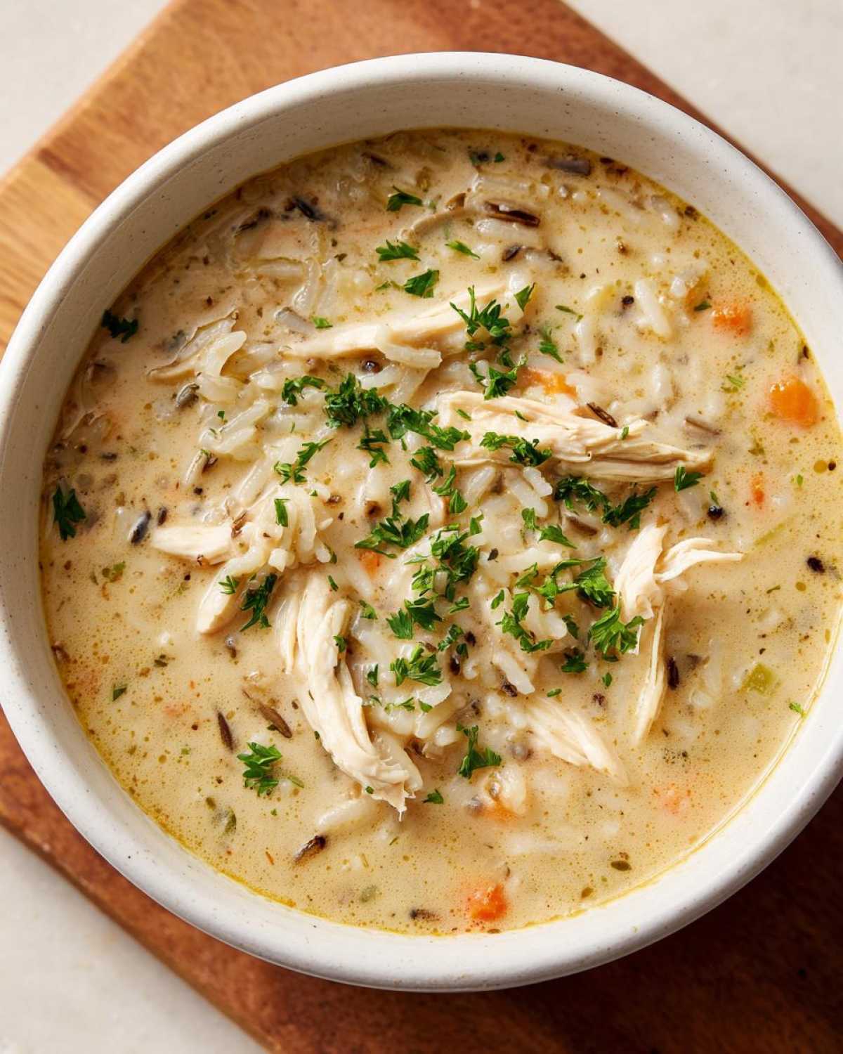 Close-up of creamy chicken wild rice soup topped with shredded chicken and fresh parsley.